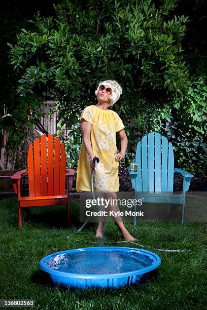 korean woman filling up small pool in backyard - 60s fashion woman stock pictures, royalty-free photos & images