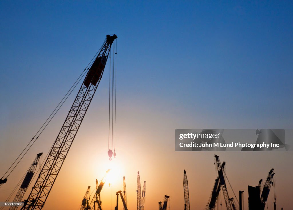 Silhouettes of cranes against sky