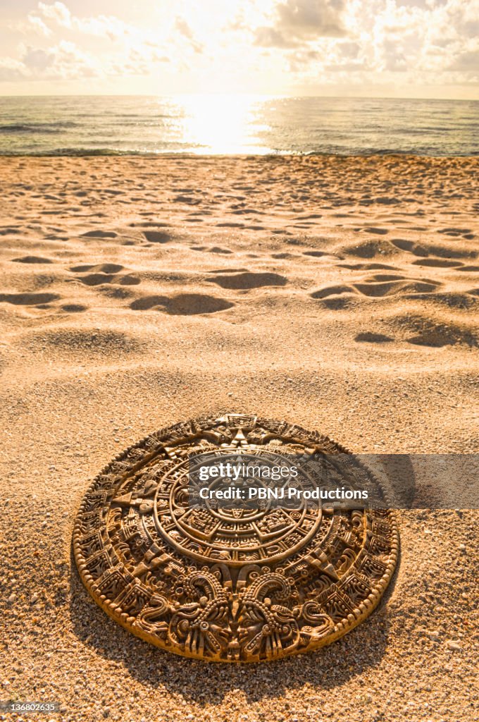 Aztec calendar stone carving on sandy beach