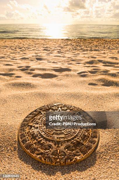 aztec calendar stone carving on sandy beach - 2012 calendar stock pictures, royalty-free photos & images