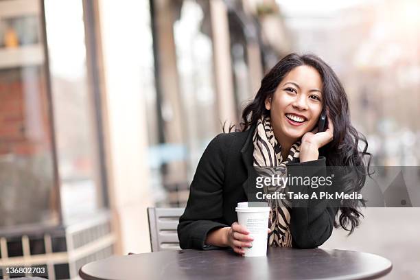 mixed race woman talking on cell phone and drinking coffee - seattle coffee stock pictures, royalty-free photos & images