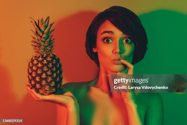 photo of hungry excited funky amazed woman hold ananas bite finger omg face isolated neon light color background - young women no clothes stock pictures, royalty-free photos & images