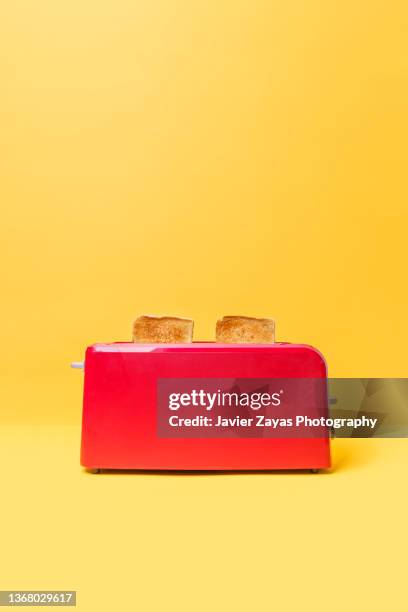 red toaster toasting two bread slices on yellow background - tosti stockfoto's en -beelden