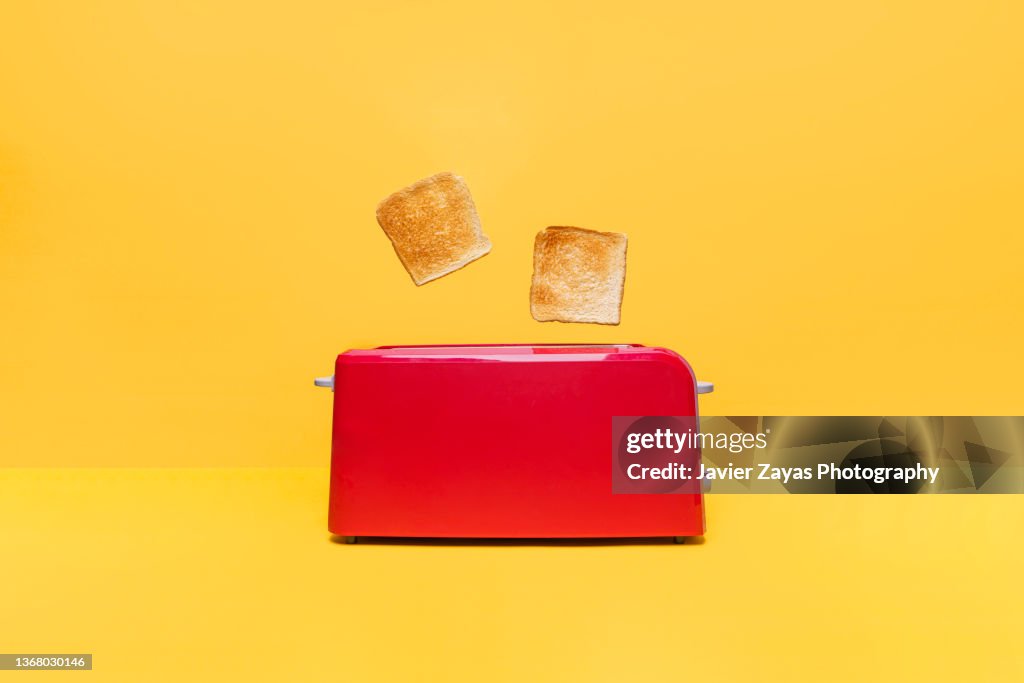 Red Toaster Toasting Two Bread Slices On Yellow Background