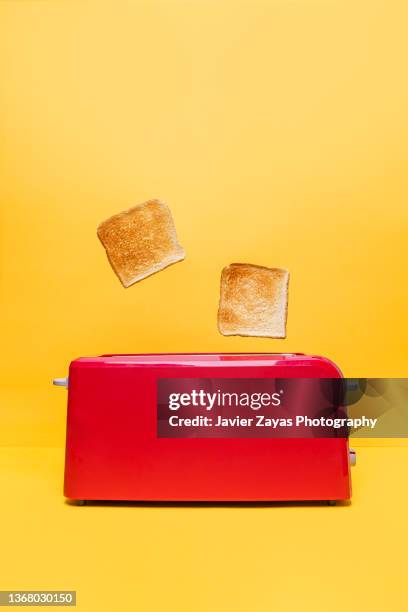 red toaster toasting two bread slices on yellow background - early termination foto e immagini stock