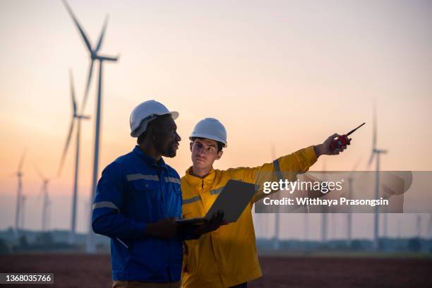 renewable energy systems. electricity maintenance engineer working on the field at a wind turbine power station at dusk - global impact stock pictures, royalty-free photos & images