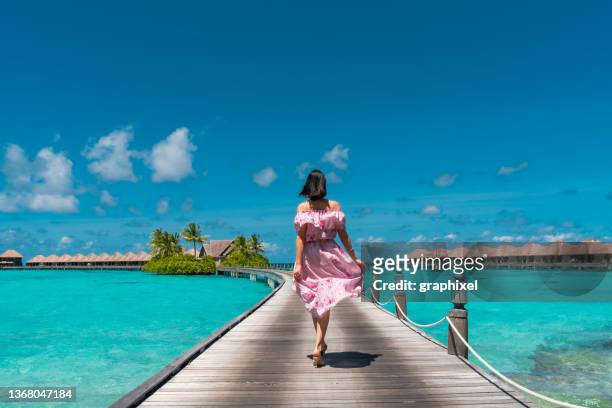 schöne frau, die auf der stegbrücke auf den malediven spazieren geht - malediven stock-fotos und bilder