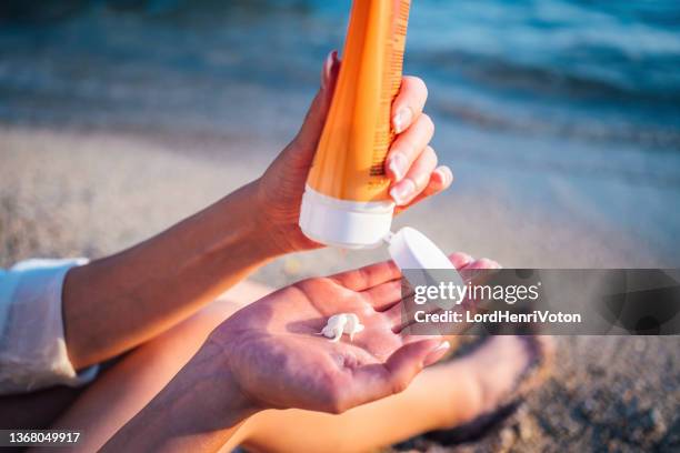 femme à l'aide de la crème solaire - lotion photos et images de collection