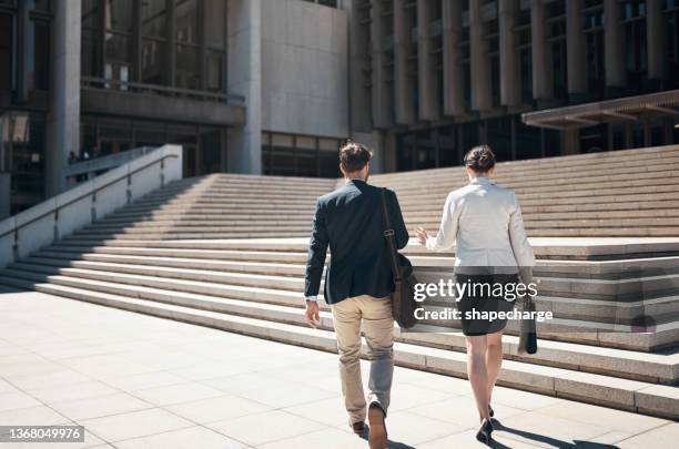 tiro de um empresário e empresária subindo um lance de escadas contra um fundo urbano - back shot position - fotografias e filmes do acervo