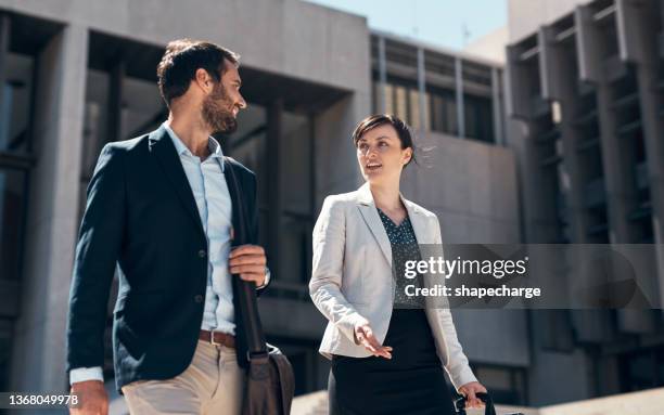 shot of a businessman and businesswoman walking and talking against an urban background - two people talking outside stock pictures, royalty-free photos & images