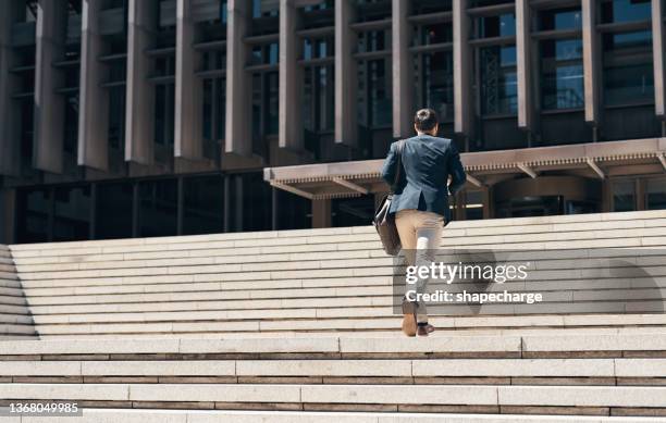 tiro de um empresário subindo um lance de escadas contra um fundo urbano - back shot position - fotografias e filmes do acervo