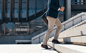 Shot of a businessman walking up a flight of stairs against an urban background