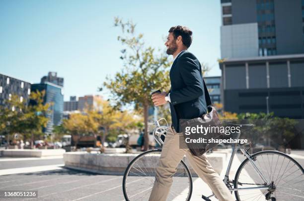 shot of a young businessman traveling through the city with his bicycle - medewerker stockfoto's en -beelden