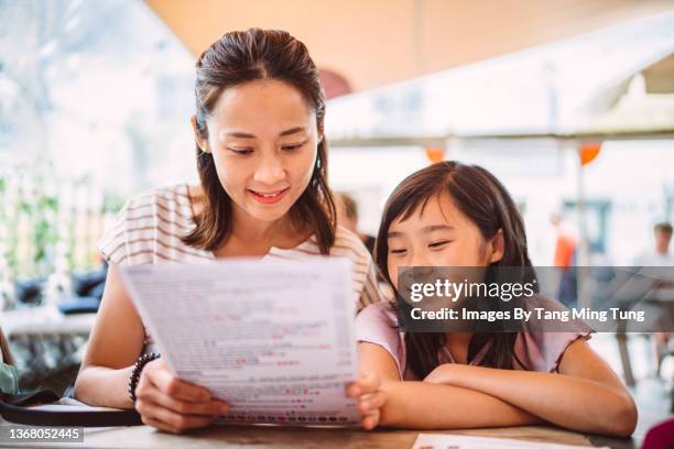 mom & daughter looking at food menu together in restaurant joyfully - kids menu photos et images de collection