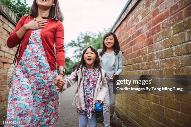 mom & daughters walking in alleyway in the town joyfully - young sister stock pictures, royalty-free photos & images