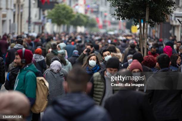 Masked and unmasked people walking in crowds on Istiklal Street, one of the most crowded places in the city on January 30, 2022 in Istanbul Turkey....