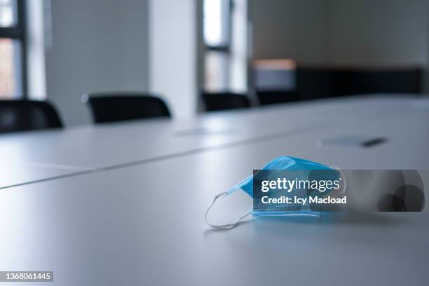 surgical mask on the table in a large meeting room with large window - covid office stock pictures, royalty-free photos & images