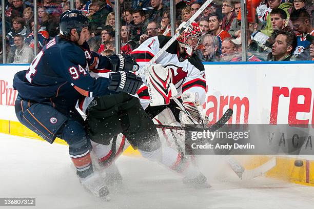 Johan Hedberg of the New Jersey Devils plays the puck away from a forechecking Ryan Smyth of the Edmonton Oilers at Rexall Place on January 11, 2012...
