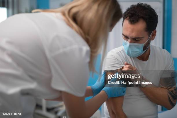 close-up of mid adult man getting vaccinated in vaccination center. - immunology stock pictures, royalty-free photos & images