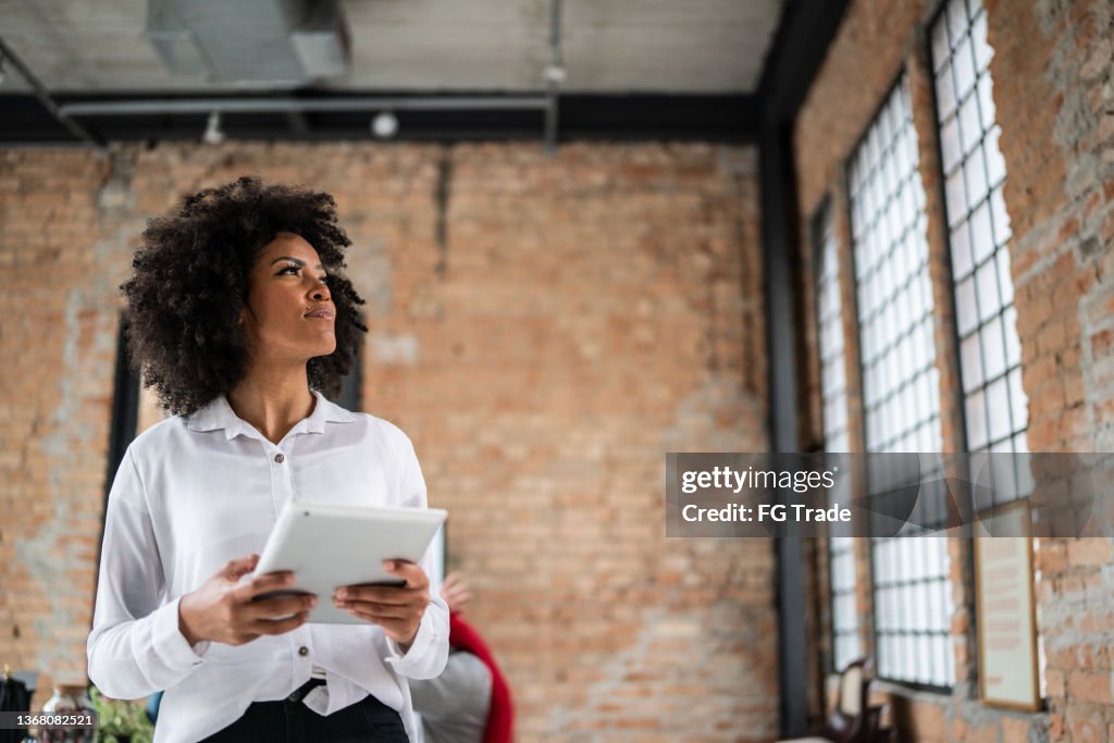 Young business woman looking away holding a digital tablet in an office