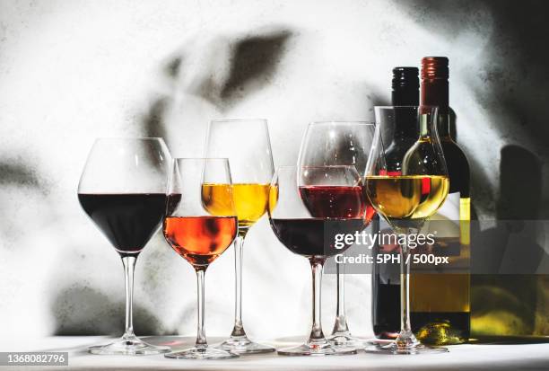 red,rose and white wine glasses set,close-up of wine bottles on table against wall - red and white wine glasses stock-fotos und bilder