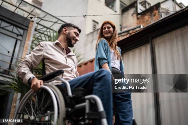 disabled man and a friend leaving office building together - mobility disability stock pictures, royalty-free photos & images