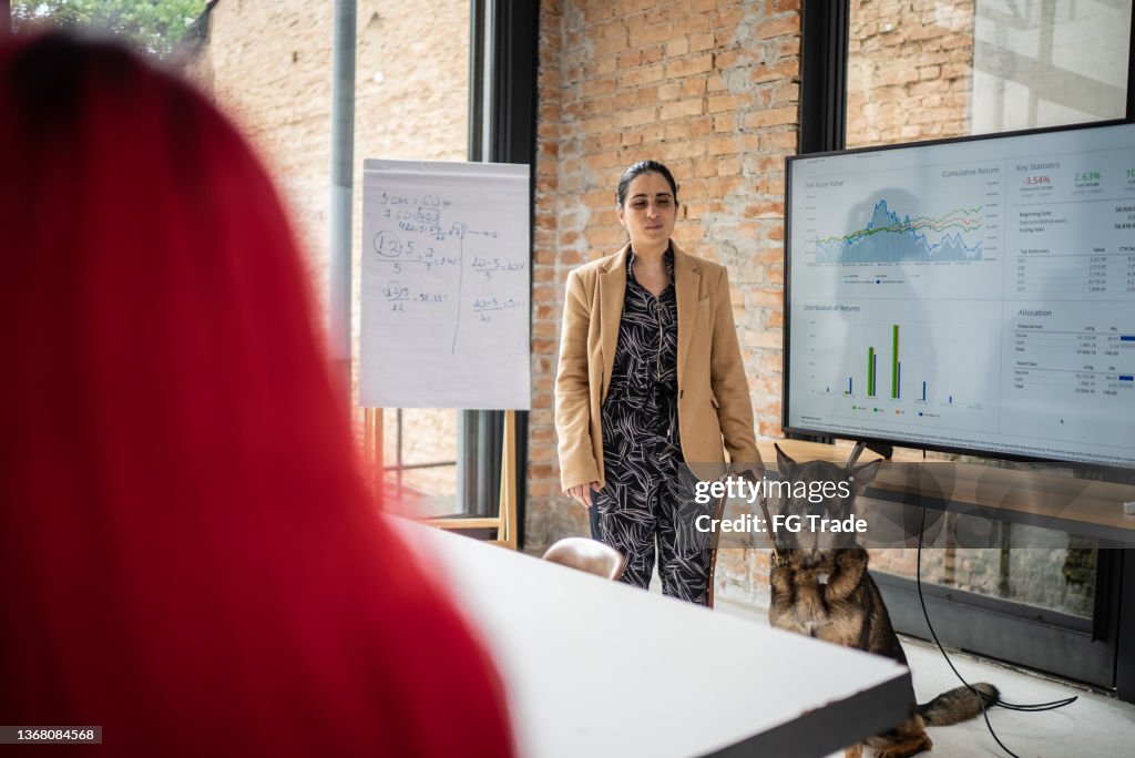 Visually impaired businesswoman doing a presentation in a business meeting with guide dog
