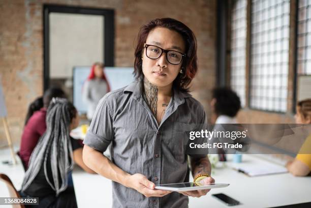 portrait of a transgender man holding a digital tablet in the office - tech founder stock pictures, royalty-free photos & images