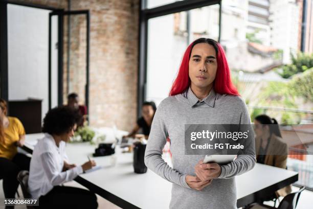 portrait of a mature man holding a digital tablet in the office - androgynous professional stock pictures, royalty-free photos & images