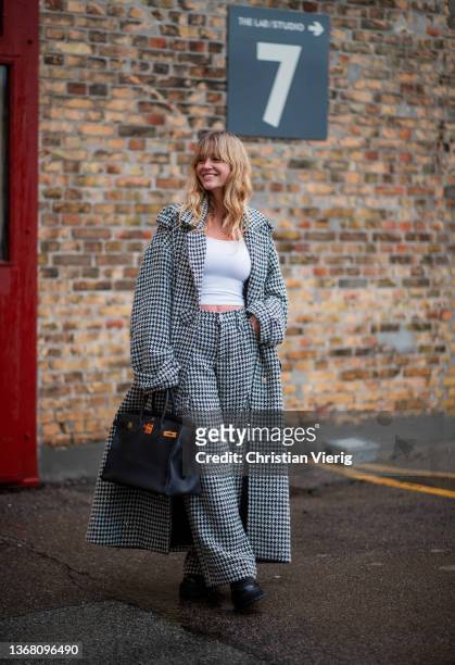 Jeanette Friis Madsen seen wearing cropped top, black white coat, pants outside Rabens Saloner during Copenhagen Fashion Week Autumn/Winter 2022 on...