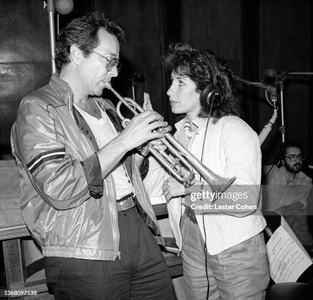 American trumpeter Herb Alpert plays his trumpet as American singer, lyricist, author and his wife, Lani Hall, listens through her headphones circa...