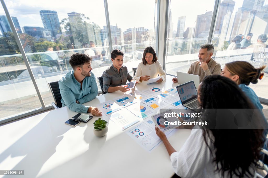 Multi racial group of people working with Paperwork on a board room table at a business presentation or seminar.