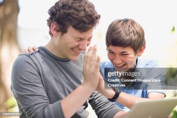 teenage boys using laptop together - internet high five stock pictures, royalty-free photos & images