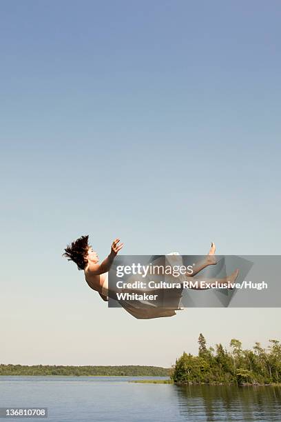 woman in dress jumping into lake - women in see through dresses stock-fotos und bilder