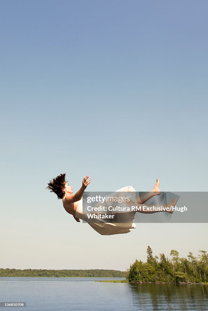 Woman in dress jumping into lake