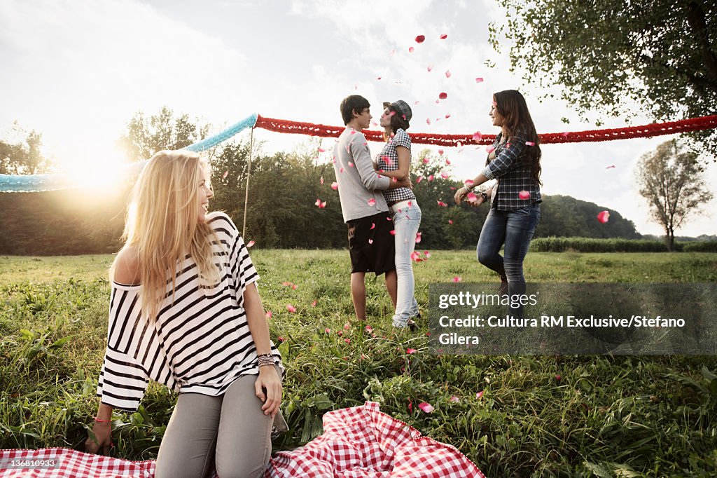 Friends throwing rose petals on couple