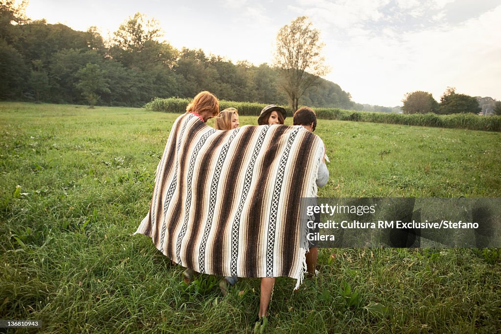 Friends wrapped in blanket in field