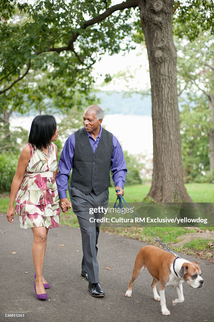 Older couple walking dog in park