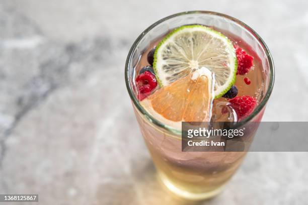 berry spritzer pouring over ice with strawberry, lemon black and red berries - crushed ice stock pictures, royalty-free photos & images