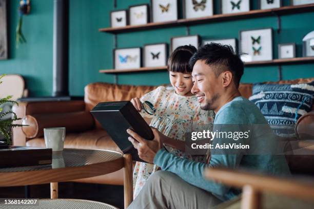 un jeune père asiatique et une charmante fille examinent ensemble des spécimens de collection d’insectes à la loupe à la maison. partager leurs passe-temps communs. concept de passe-temps et d’intérêts - prélèvement à tester photos et images de collection
