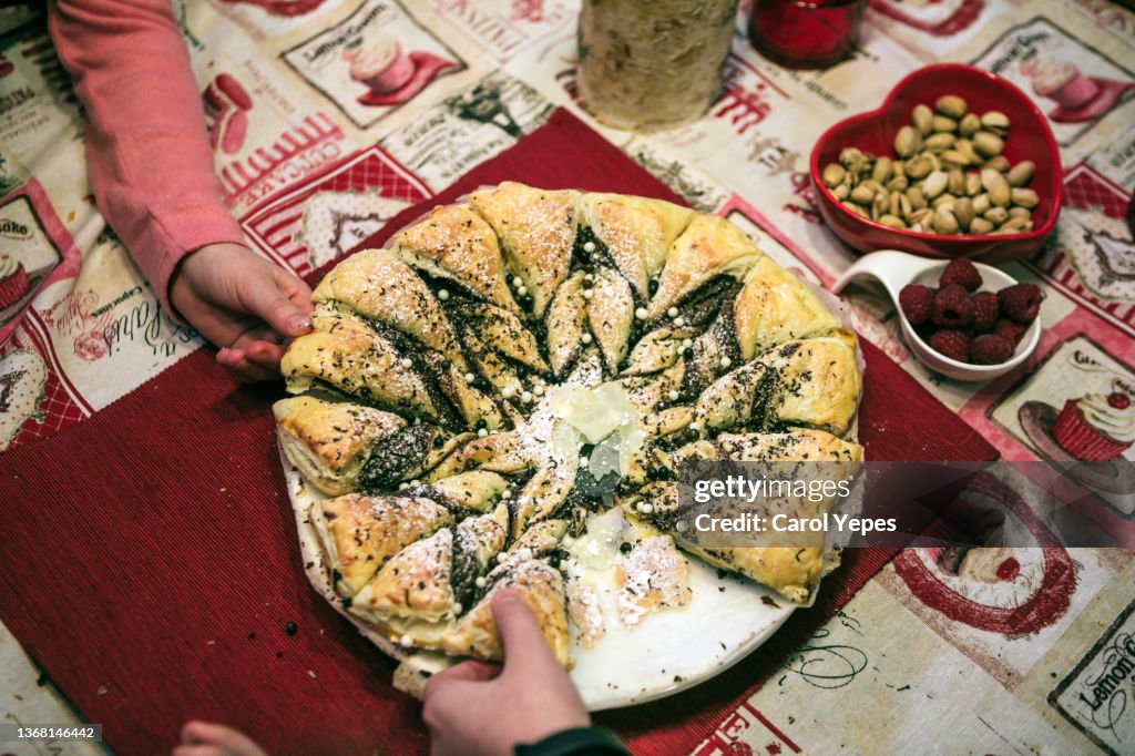 Kids hand reaching for cake pie on the table at the dining roo,.Top view