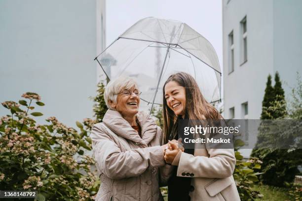 cheerful senior woman talking with female healthcare worker in park - caregiver and senior foto e immagini stock