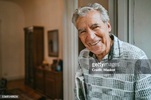 portrait of smiling senior man at home - rentnersiedlung stock-fotos und bilder