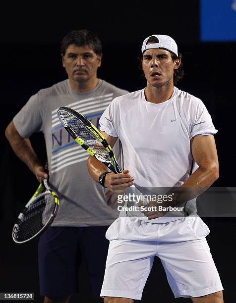 Rafael Nadal of Spain prepares to play a shot as he is watched by Toni Nadal, his uncle and coach during practice ahead of the 2012 Australian Open...
