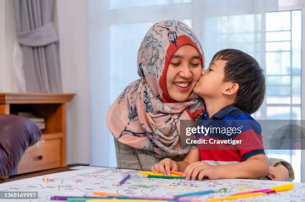 the muslim mother helping son with painting activity for homework at home. - arab student kids stock pictures, royalty-free photos & images