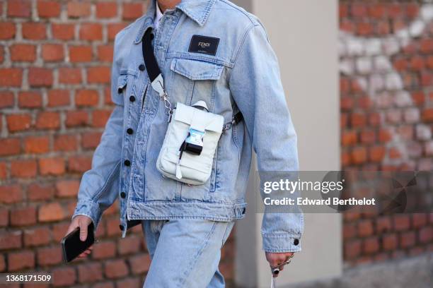 Guest wears a white shirt from Fendi, a blue faded denim jacket from Fendi, a white gray nylon crossbody bag from Fendi, blue faded denim large jeans...