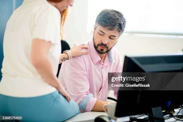 uncomfortable businessman being harassed by a female coworker at his desk - sexual harassment stock pictures, royalty-free photos & images