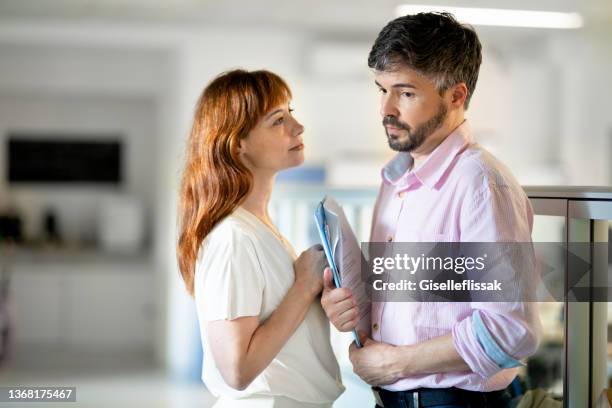 businessman looking annoyed by the unwanted advances of a female coworker - sexual harassment stock pictures, royalty-free photos & images