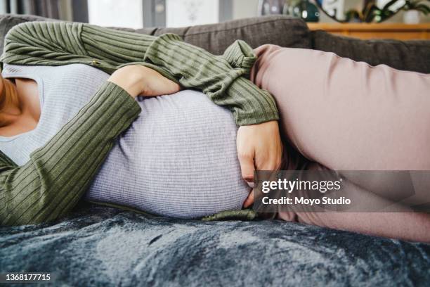 aufnahme einer schwangeren frau, die ihren bauch streichelt - muskelkontraktion stock-fotos und bilder