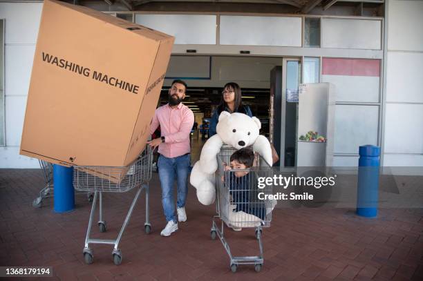 family leaving large appliance store with washing machine. - buying washing machine stockfoto's en -beelden